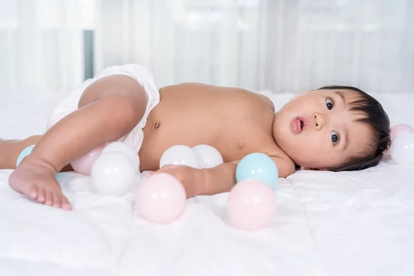 Bebê jogando bola de cor em uma cama — Fotografia de Stock