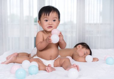 yatakta ikiz bebekler, bir oyun renk topu, bir uyku