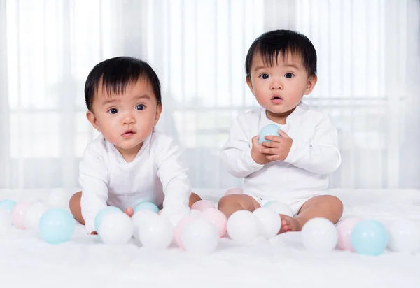 Cheerful twin babies playing color ball on  bed — Stock Photo, Image