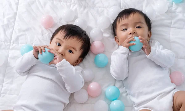 Веселые близнецы играют в цветной мяч на кровати — стоковое фото