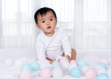 neşeli bebek yatakta renk topu oynuyor