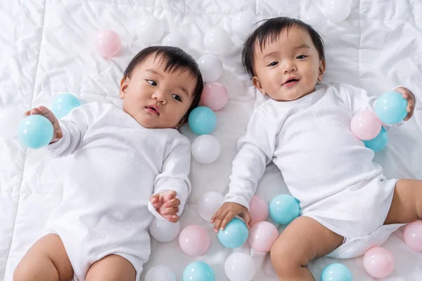 Bebês gêmeos alegres jogando bola de cor na cama — Fotografia de Stock