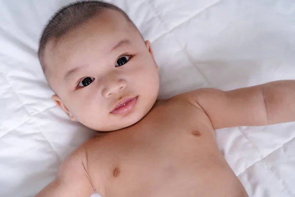 Happy baby lying on a bed — Stock Photo, Image