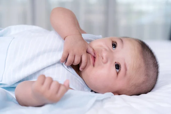 Baby mit Finger im Mund auf einem Bett — Stockfoto