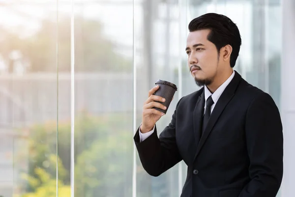 Hombre de negocios pensando y sosteniendo una taza de café en la oficina — Foto de Stock