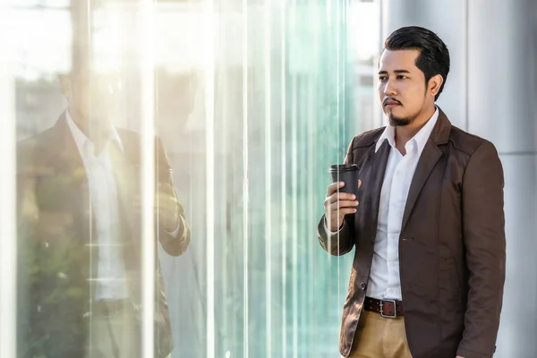 Człowiek biznesu myślenia i trzymając filiżankę kawy w biurze — Zdjęcie stockowe