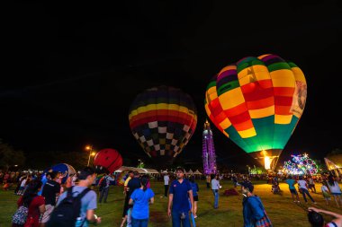 Air balloons glow with burner flame glowing in night at Nakhon R