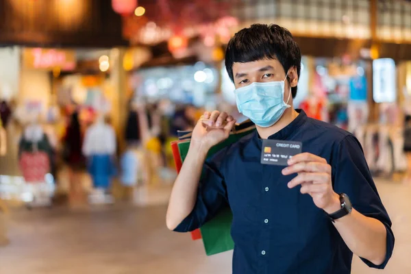 Joven Hombre Asiático Con Máscara Médica Celebración Una Tarjeta Crédito —  Fotos de Stock