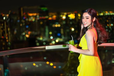 Gece elbisesi içinde güzel bir kadın kokteyl tutuyor.