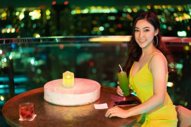 Gece vakti restoranda elinde kokteyl tutan gece elbisesi giymiş güzel bir kadın.