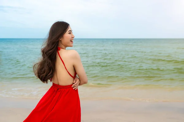 身穿红衣服 手挽手站在海滩上的快乐女人 — 图库照片