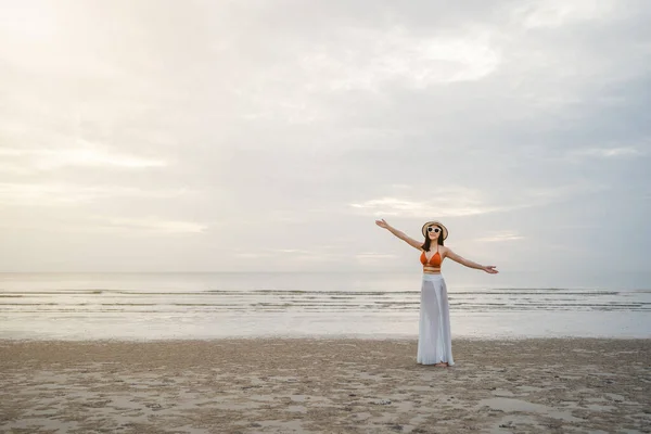 freedom woman in bikini walking with arms raised on the sea beach