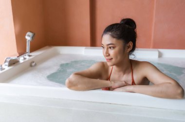 Bikinili kadın küvette dinleniyor.