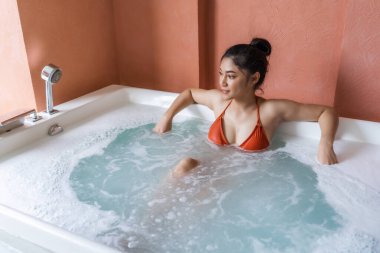 Bikinili kadın küvette dinleniyor.