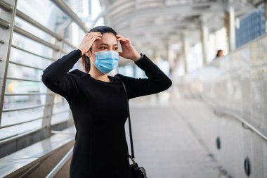İş kadınlarının başağrısı vardır ve Coronavirus (covid-19) salgınından korunmak için tıbbi maske takarlar.