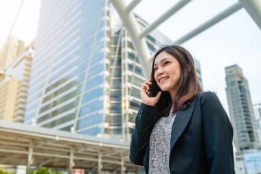 Şehirde cep telefonuyla konuşan mutlu bir iş kadını.