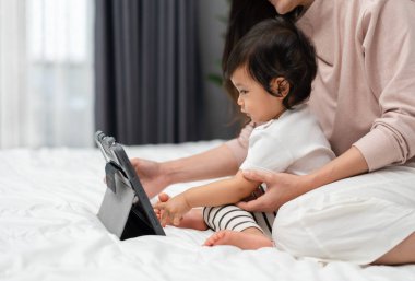 Bebekle anne yatakta dijital tablet bilgisayar kullanıyor.