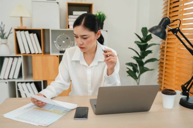 Evrak ve bilgisayarla çalışan stresli genç bir kadın.