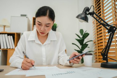Akıllı telefon kullanan ve belge yazan bir iş kadını. Merkez büroda çalışıyorum.