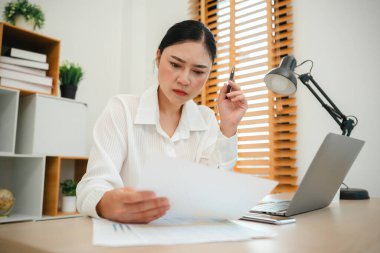 Evrak ve bilgisayarla çalışan stresli genç bir kadın.