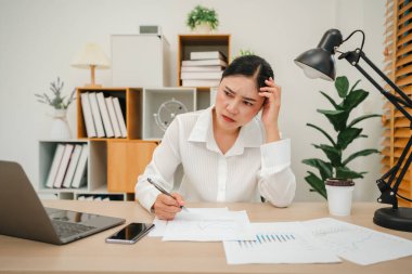 Evrak ve bilgisayarla çalışan stresli genç bir kadın.
