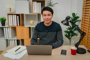 Merkez ofiste dizüstü bilgisayarla çalışan mutlu genç adam.