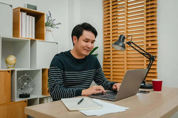 Merkez ofiste dizüstü bilgisayarla çalışan mutlu genç adam.