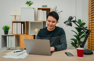 Merkez ofiste dizüstü bilgisayarla çalışan mutlu genç adam.