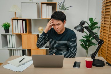 Ofiste dizüstü bilgisayarla çalışırken adamın başı ağrıyor.