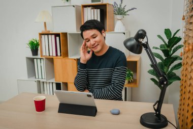 Ofisteki müzik ve tablet dinlemek için kablosuz kulaklık kullanan mutlu genç adam.