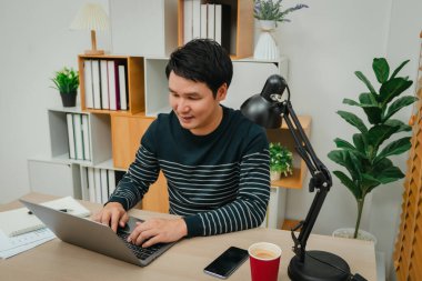 Merkez ofiste dizüstü bilgisayarla çalışan mutlu genç adam.