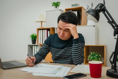 Evrak ve bilgisayarla çalışan stresli genç adam.