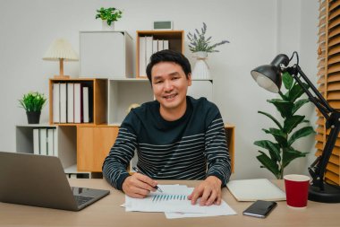 Mutlu bir adam ofis bilgisayarında belge ya da evrak yazıyor.