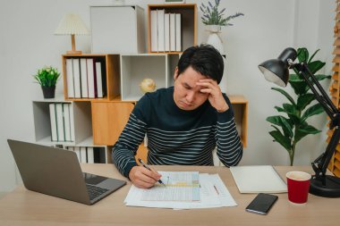 Evrak ve bilgisayarla çalışan stresli genç adam.