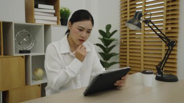 Kadın evdeki ofiste dijital tablet kullanırken düşünüyor