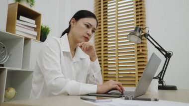 Genç bir kadın evdeki bilgisayarla düşünüyor ve çalışıyor.