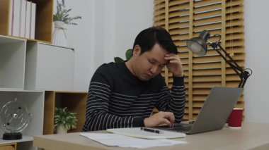 Ofiste dizüstü bilgisayarla çalışırken adamın başı ağrıyor.