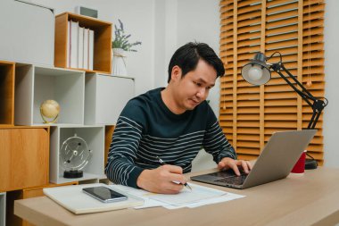 man working with laptop computer and document at home office