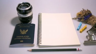 Boş kitap ve vintage objektif, Tayland resmi pasaport ve beyaz renk arka plan üzerinde küçük çiçek tasarım çalışmak için kalem düz yatıyordu görüntüleri.