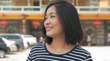 Esen rüzgar seyir siyah saçlı gülümseyen genç Asya kadın portresi kapatın ve arka plan yavaş hareket bulanıklığı