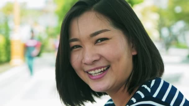 Närbild porträtt av unga Asien kvinna leende med svart hår som blåser i vinden inne och oskärpa bakgrunden slowmotion — Stockvideo