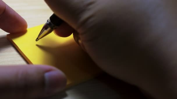 Mannen een dank op een papier notitie schrijven met een blauwe pen en Softfocus scène. — Stockvideo