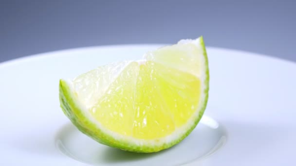 Свіжий зелений шматочок лимона повільно обертається в студії з деталями . — стокове відео