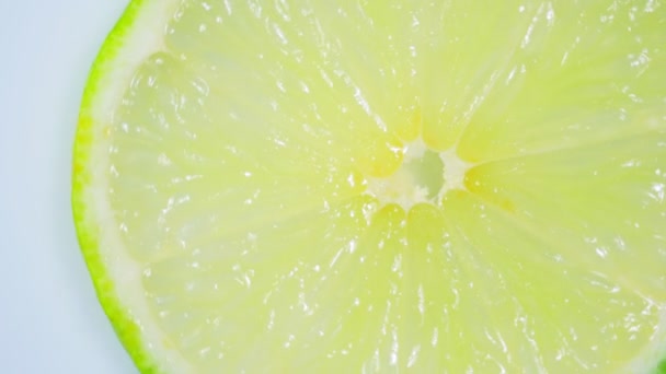 Fresh green lemon slice is slowly rotating in the studio with the details. — Stock Video
