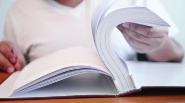 Bir adam masadaki birçok sayfayı hızlıca açarak bilgi edinmek için büyük kitapları açıyor..