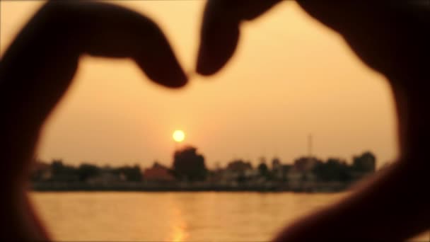 L'ombre de la main d'une femme a fait une forme de coeur et le soleil tombe à côté de la forme et près de la zone colorée de la rivière . — Video