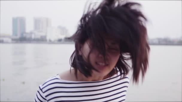 Närbild porträtt av ung asiatisk kvinna ler och svep huvud och hår med svart hår som blåser i vinden och tittar på solnedgången nära floden. Kvinna som bär är en rutig skjorta med Slow Motion. — Stockvideo