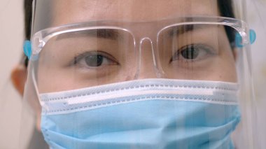 Gözlüklerini ve gözlerini korumak için yüzünün etrafına maske takmış Asyalı genç bir kadının portresi yeni bir normalliğe hazırlanıyor. Koronavirüs salgını.