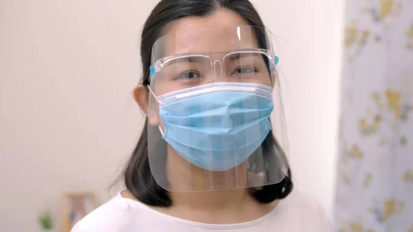 Portrait of an Asia young female who is wearing a face shield with mask rounded around her face from a frontal perspective to protect her glasses and eyes prepare to new normal. Coronavirus pandemic.