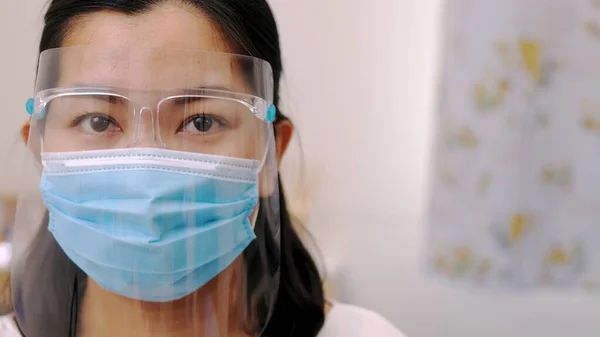 Portrait of an Asia young female who is wearing a face shield with mask rounded around her face from a frontal perspective to protect her glasses and eyes prepare to new normal. Coronavirus pandemic.